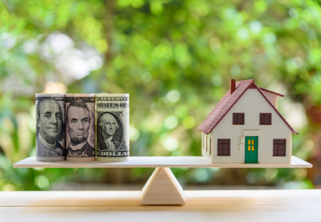 Home loan / reverse mortgage or transforming assets into cash concept : House model, US dollar notes on a simple balance scale, depicts a homeowner or a borrower turns properties / residence into cash